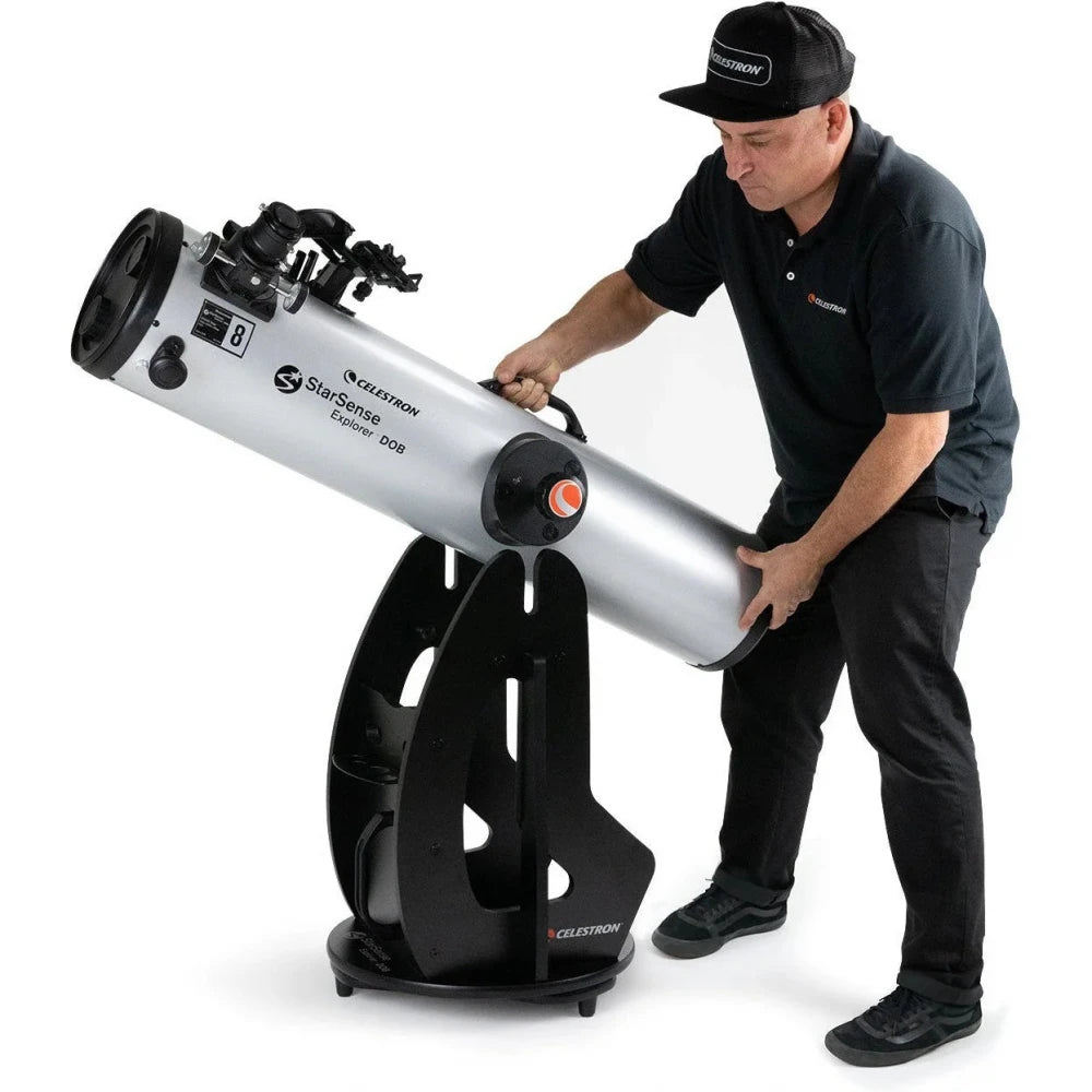 Person holding a Celestron telescope on a white background
