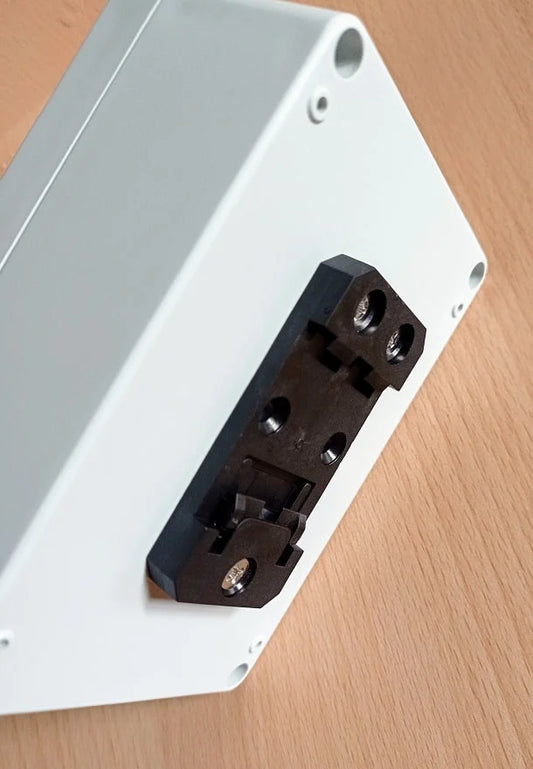 Close-up of a white electronic component with black connectors on a wooden surface